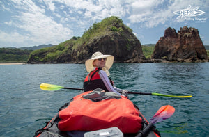 Two neris kayakers paddling in Indonesia. One is taking the picture, while the other one is looking back